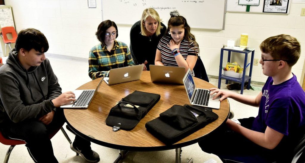 Kim Quinn Hutchinson, executive director of a computer science pilot program funded by an $881,000 grant from the Harold Alfond Foundation, assists Waterville Junior High School students, from left, Dylan Mitchell, Alexa DeWitt, Leilani Gomez and Zachary London.