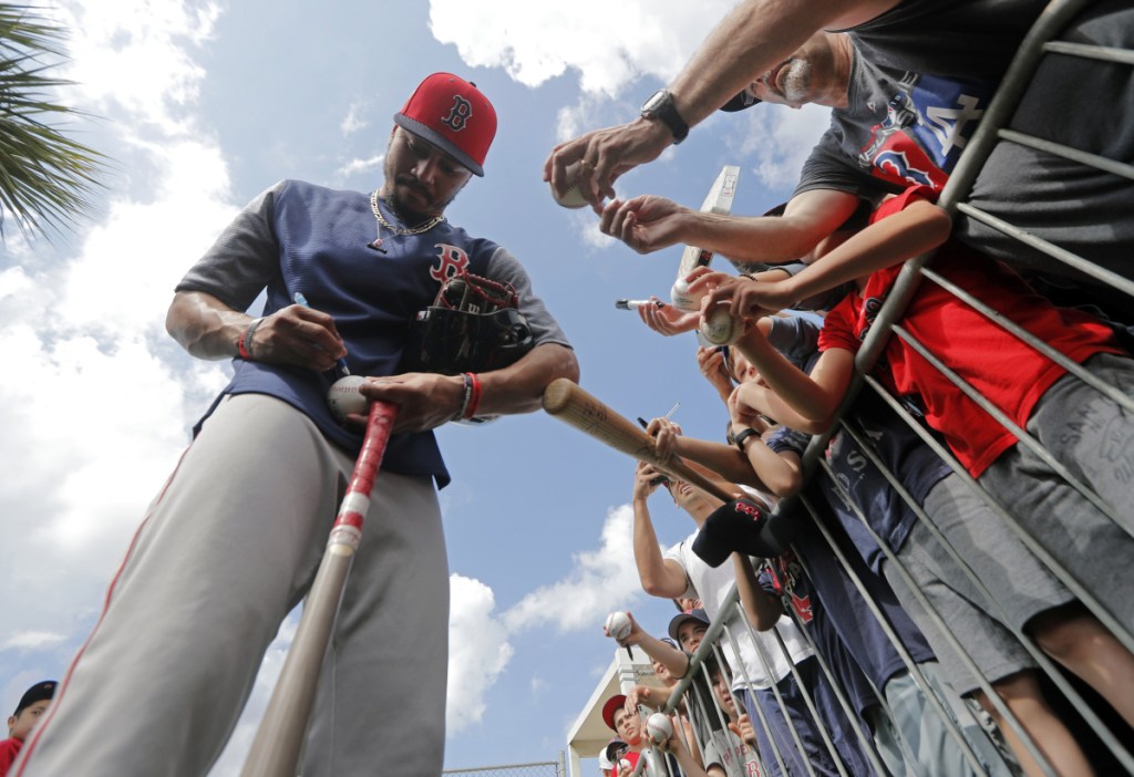 Center fielder Mookie Betts of the Boston Red Sox signs autographs for fans Monday during the team's first full-squad workout at spring training in Fort Myers, Fla.