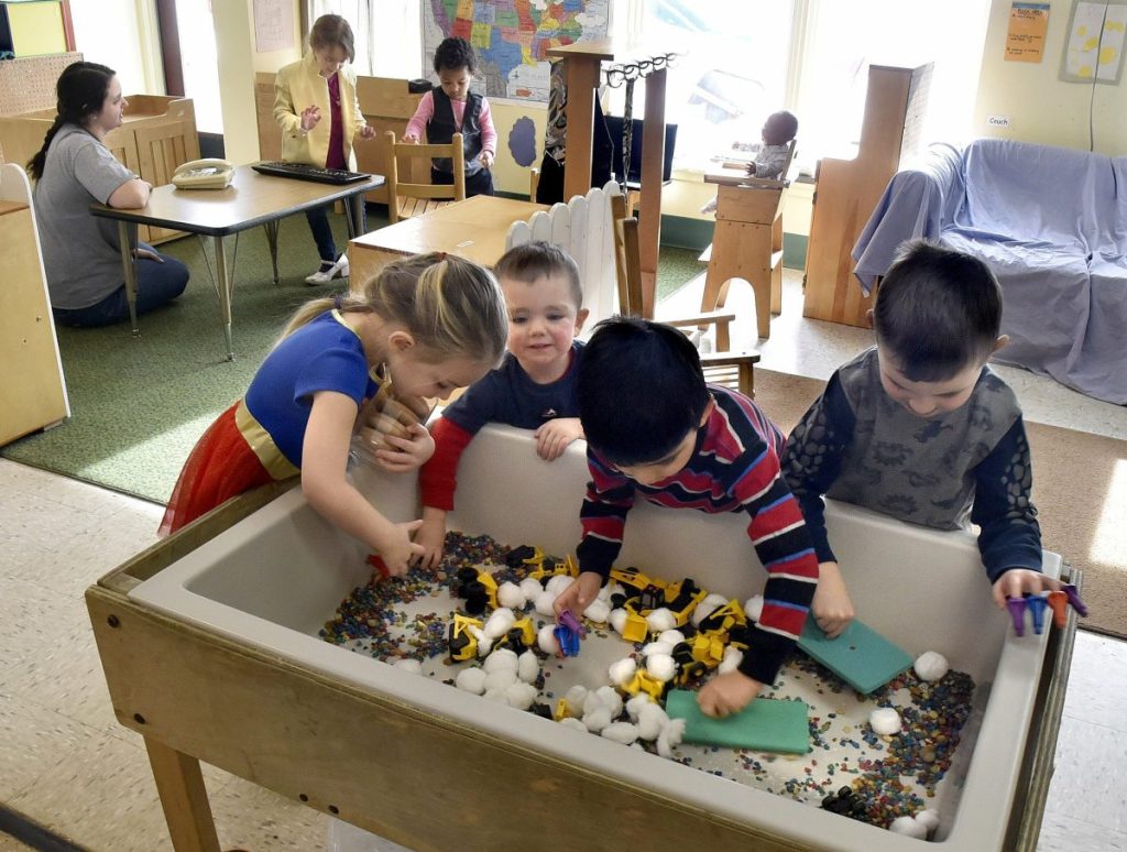 Above: As University of Maine at Farmington student Jocelyn Rocray works with children in the background, others play at the Sweatt-Winter Child Care and Early Education Center on Tuesday morning. Bottom: A boy shows off his fingers while playing with a puzzle at the center on Tuesday.