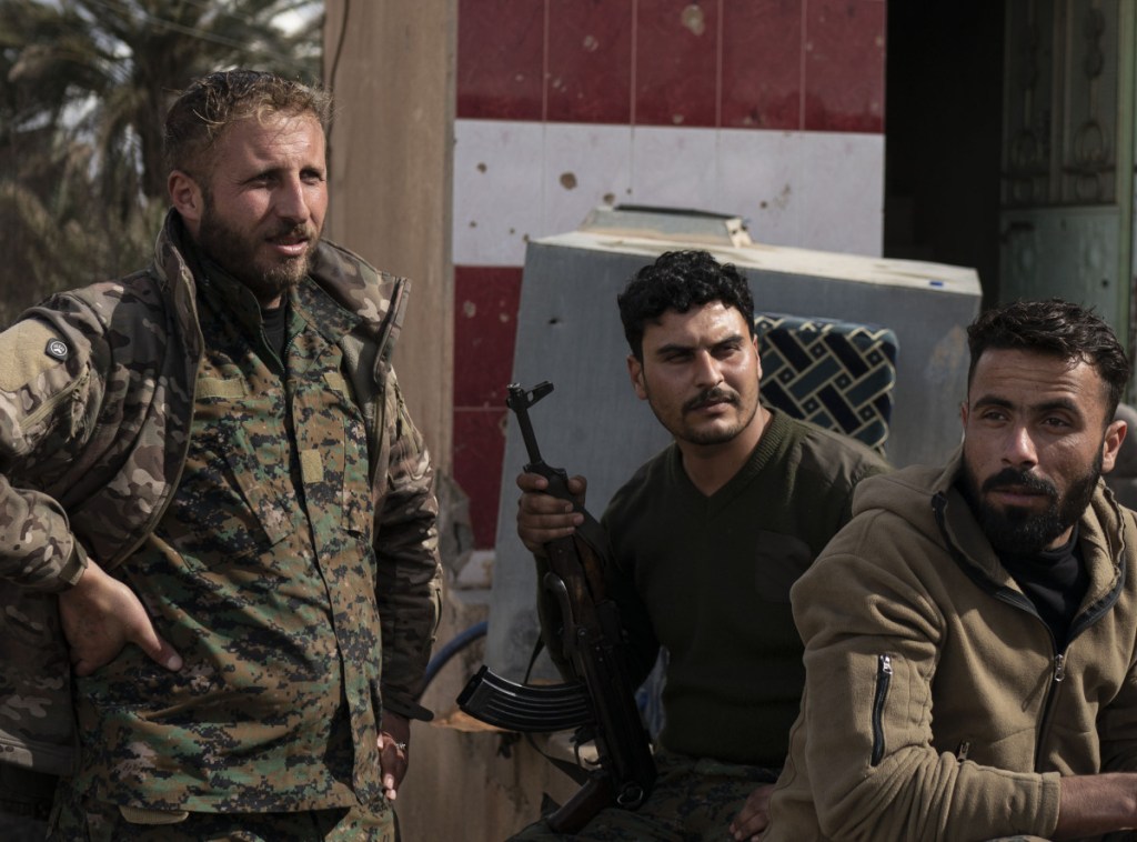 U.S.-backed Syrian Democratic Forces fighters wait outside a temporary base near the last land still held by Islamic State militants in Baghouz, Syria, Monday.