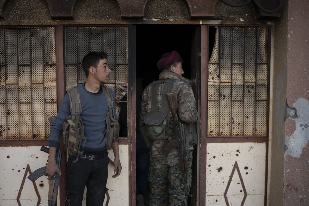 U.S.-backed Syrian Democratic Forces (SDF) fighters enter a building used as a temporary base near the last land still held by Islamic State militants in Baghouz, Syria, Monday, Feb. 18, 2019. Hundreds of Islamic State militants are surrounded in a tiny area in eastern Syria are refusing to surrender and are trying to negotiate an exit, Syrian activists and a person close to the negotiations said Monday.