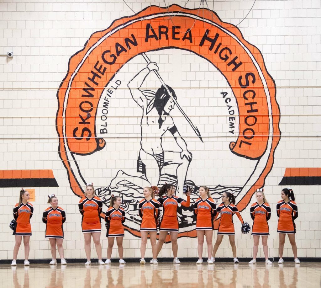 Skowhegan Area High School cheerleaders stand beneath the Indian mural on the wall of the gymnasium. Skowhegan is the only school left in Maine that still uses the "Indians" nickname for its sports teams.