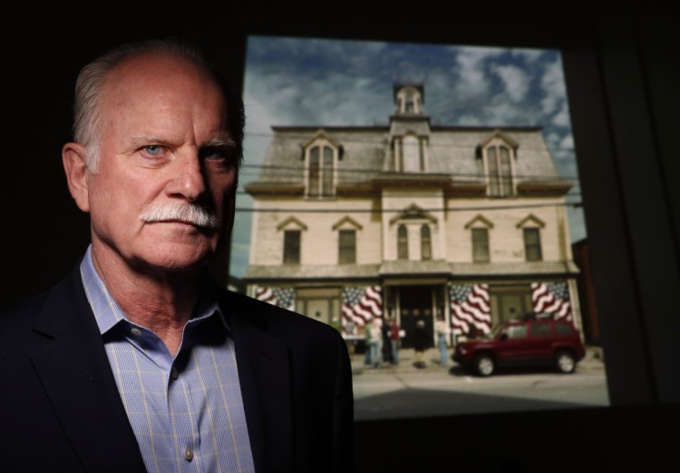 Larry Sterrs poses with an image of Star of Hope, the home of artist Robert Indiana. Sterrs is leading efforts to turn the Vinalhaven home into a museum.