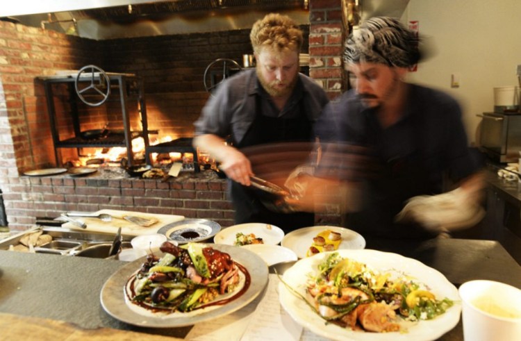 Cooks Matt Jauck, left, and Sean Kach prepare plates last July at Walkers Maine in Cape Neddick. The restaurant, awarded Four Diamonds this year, re-opens March 14 with a new spring menu.