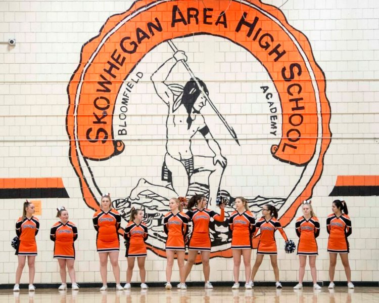 Skowhegan Area High School cheerleaders stand beneath the Indian mural on the wall of the gymnasium on Jan. 15, 2019.