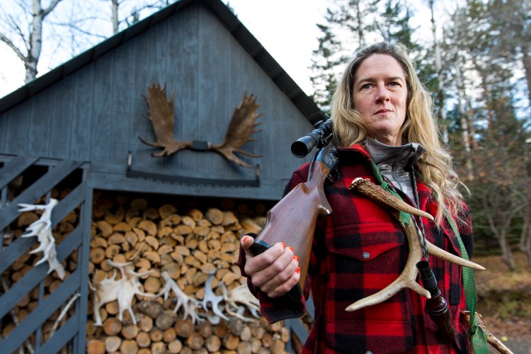 Liz Walker rests her Remington 7600 on her shoulder near a woodshed outside her Rangeley home. 