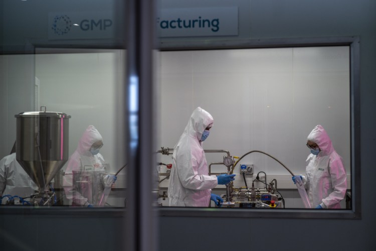 Scientists re-enact the calibration procedure of equipment at an Afrigen Biologics and Vaccines facility Oct. 19 in Cape Town, South Africa. In a pair of warehouses converted into a maze of airlocked sterile rooms, young scientists are assembling and calibrating the equipment needed to reverse engineer a coronavirus vaccine that has yet to reach South Africa and most of the world's poor.