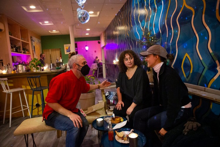 Cocktail Mary owner Isaac MacDougal talks to patrons Jackie Murray of Chicago and Stephanie Petrella, right, of New York City on Wednesday evening. Some Portland restaurant owners support a proposed citywide vaccine mandate for indoor dining, but others disagree.