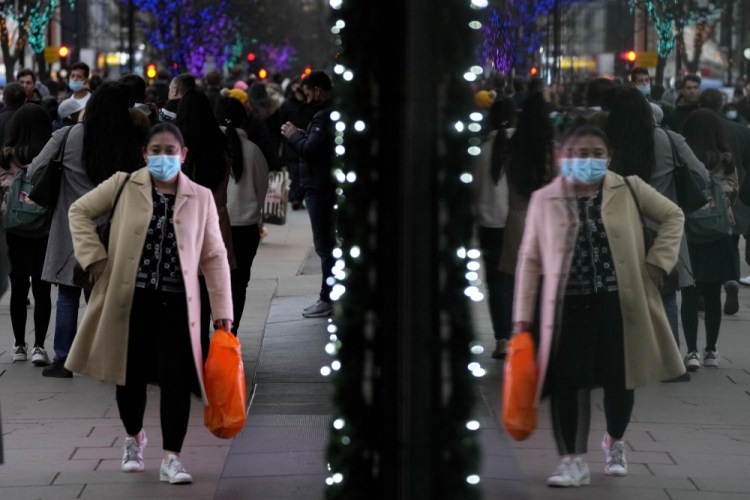 Shoppers are reflected in a window as they walk down Oxford Street, Europe's busiest shopping street, in London on Thursday.