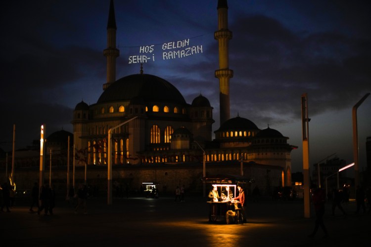 People buy roasted chestnuts next to Taksim mosque as the sun sets during the first day of the Muslim holy  month of Ramadan, in Istanbul, Turkey, on Saturday.