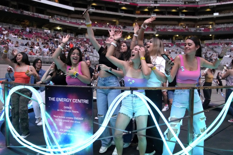 Concertgoers dance on a kinetic floor during Coldplay's "Music of the Spheres" tour on Thursday at State Farm Stadium in Glendale, Ariz. The tour stage uses recycled steel, and the band hopes to deploy the world’s first tour battery system, made from 40 repurposed and recyclable BMW electric car batteries. The hope is to power the entire show from batteries, never needing the grid or diesel generators.